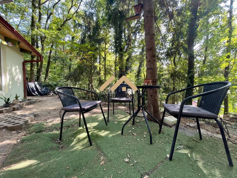 A cottage in Kučišdorská Valley, Pezinok, with outdoor seating surrounded by forests.