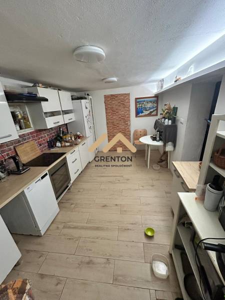 A kitchen in a cabin with a wood-patterned floor, light cabinets, and a dining table.