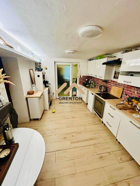 A kitchen in a cabin with a wood-decor floor and white furniture.