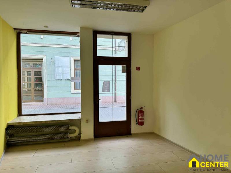 Commercial premises with a large window, wooden decor flooring, and a fire extinguisher.