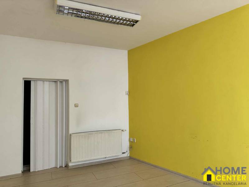 Interior of commercial spaces with wood-patterned flooring and a yellow wall.