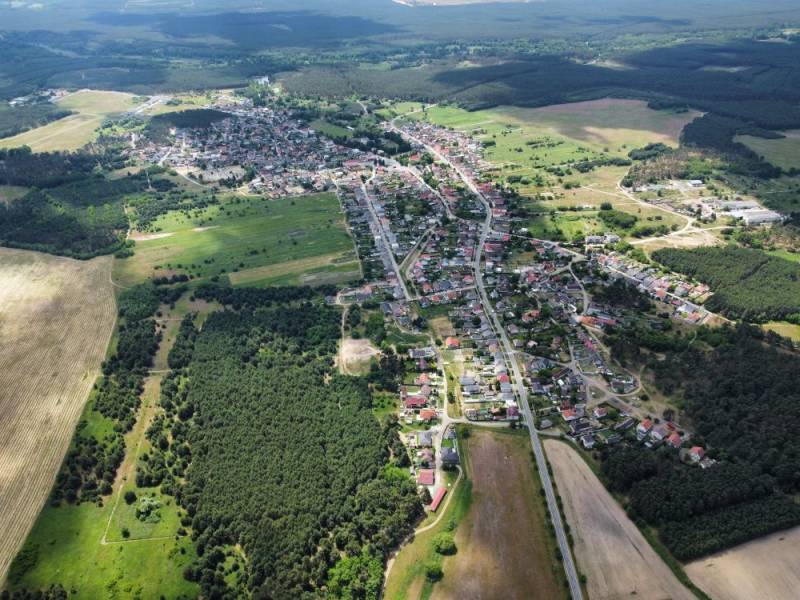 Aerial view of agricultural and forest land in Studienka with visible buildings and forests.