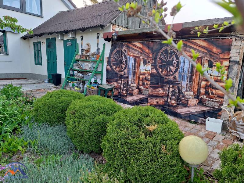 A family house in Okoličná na Ostrove with a decorative wooden wall and a landscaped garden.