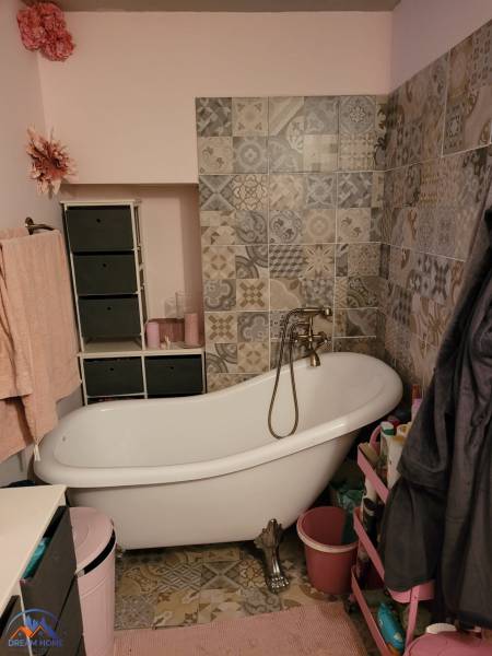 A bathroom in a family house with a freestanding bathtub and patterned tiles on the wall.