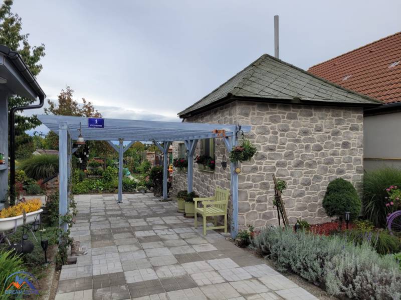 A family house in Okoličná na Ostrove with a stone annex and garden benches.