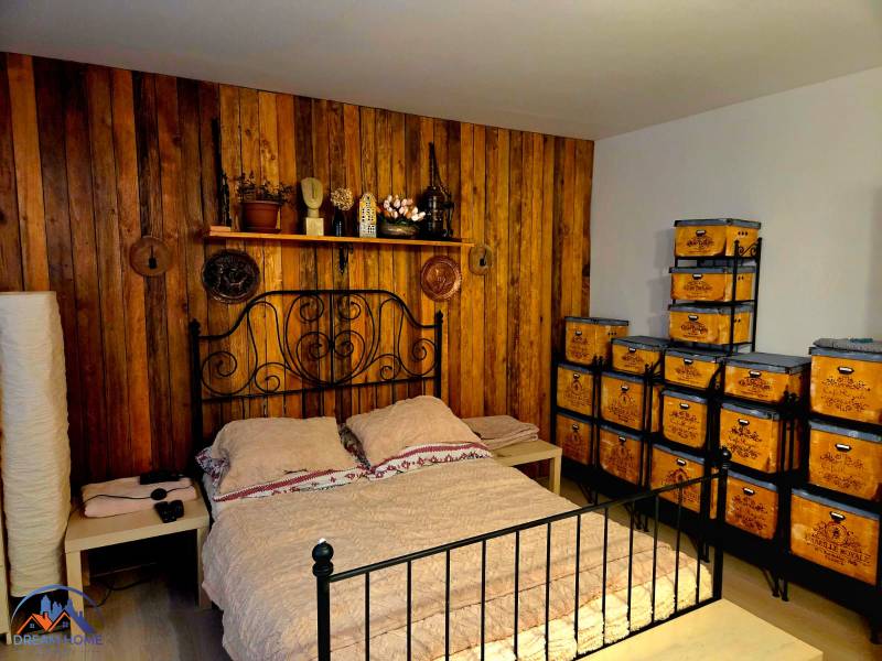 A bedroom in a family house with wooden paneling, a metal bed, and storage boxes.