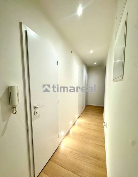 A hallway with light walls and a floor with a wooden decor in a 4-room apartment.