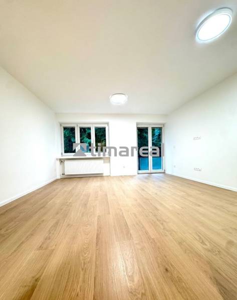 Interior of a 4-room apartment with a wooden decor floor, white walls, and windows.