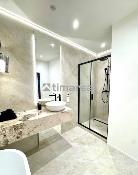Bathroom with a shower, a sink on a stone countertop, and light tiling in a 4-room apartment.