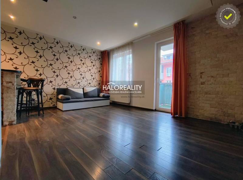 Living room in a two-room apartment with patterned wallpaper and wood-decor flooring.