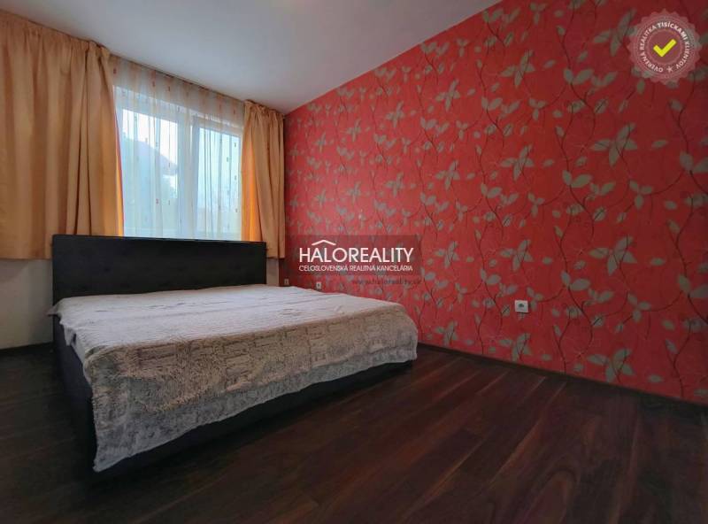 Bedroom in a 2-room apartment with red floral wallpaper and a wooden decor floor.