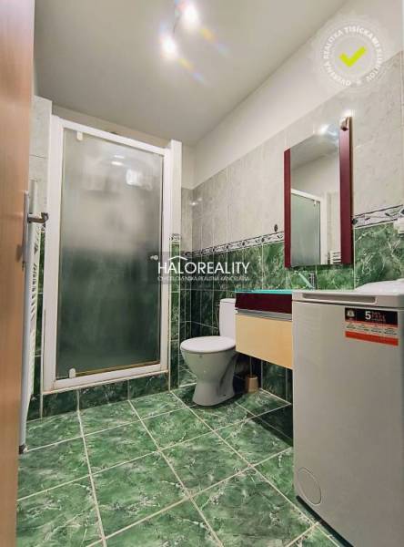 Bathroom in a 2-room apartment with a toilet, shower, washing machine, and green tiles.