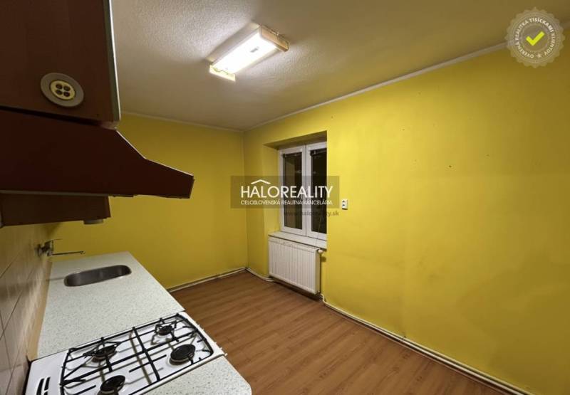 A kitchen in a 2-room apartment with a wood-patterned floor and yellow walls.