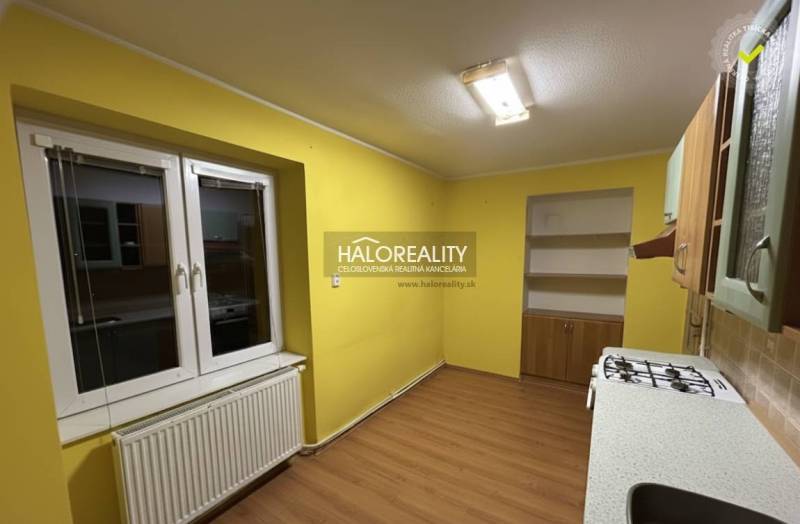 A kitchen in a 2-room apartment with yellow walls and a wooden decor floor.