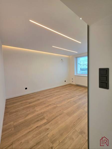 A room with a wooden decor floor in a 3-room apartment, with LED ceiling lighting.