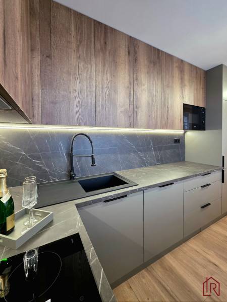 A kitchen in a 3-room apartment with a kitchen unit, a wooden decor floor, and marble tiles.