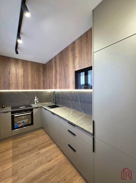 The kitchen of a three-room apartment with a wooden-patterned floor and speckled gray countertops.