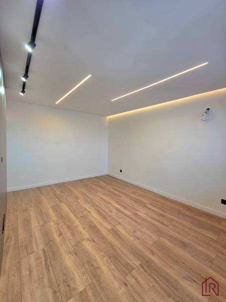 Interior of a 3-room apartment with white walls and a floor with a wood decor, lighting.