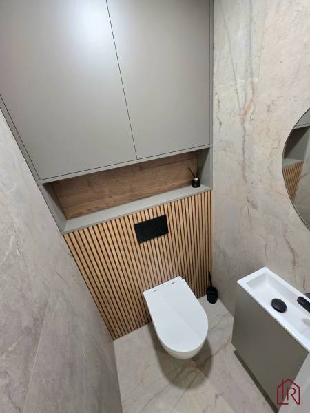 A toilet with vertical tiling, a mirror, and a storage cabinet in a 3-room apartment.