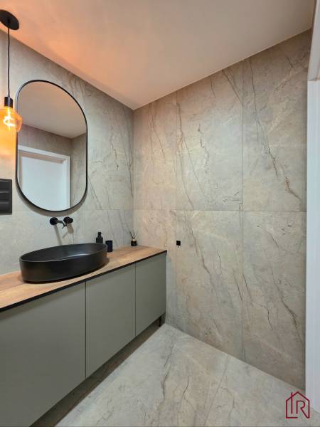 Bathroom in a 3-room apartment with a sink on a wooden decor and a black light fixture.