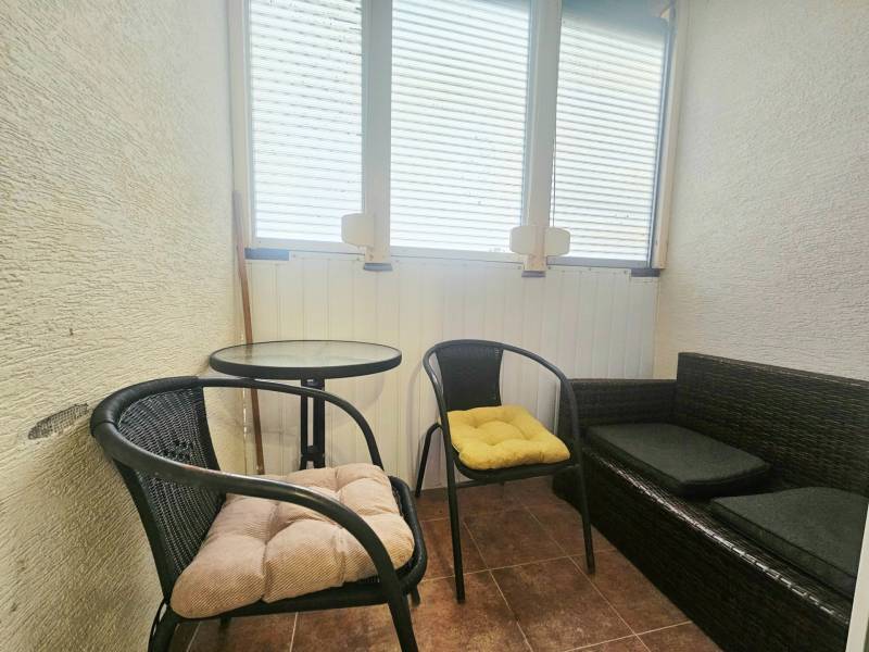 A balcony in a 3-room apartment with seating, chairs, and a table.