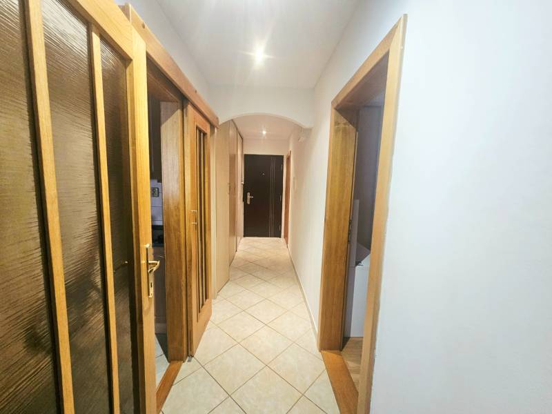 A hallway with a tiled floor, doors with a wooden decor in a 3-room apartment.