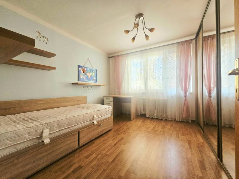 Children's room in a 3-room apartment with a bed, cabinets, and a wooden decor floor.