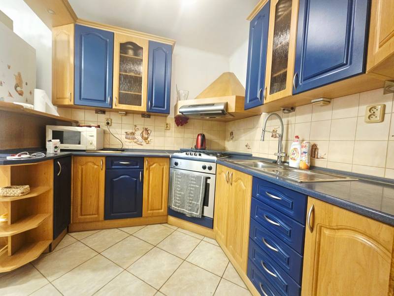 A kitchen in a 3-room apartment with ceramic tiles and blue cabinets.