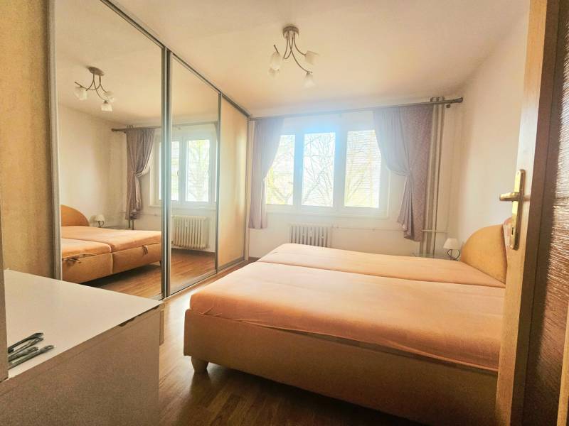 Bedroom in a 3-room apartment with a bed, built-in wardrobe, and floor with wooden decor.