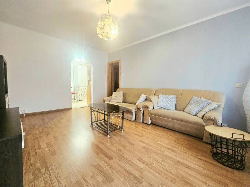 Living room in a 3-room apartment with a beige sofa and a wooden decor floor.