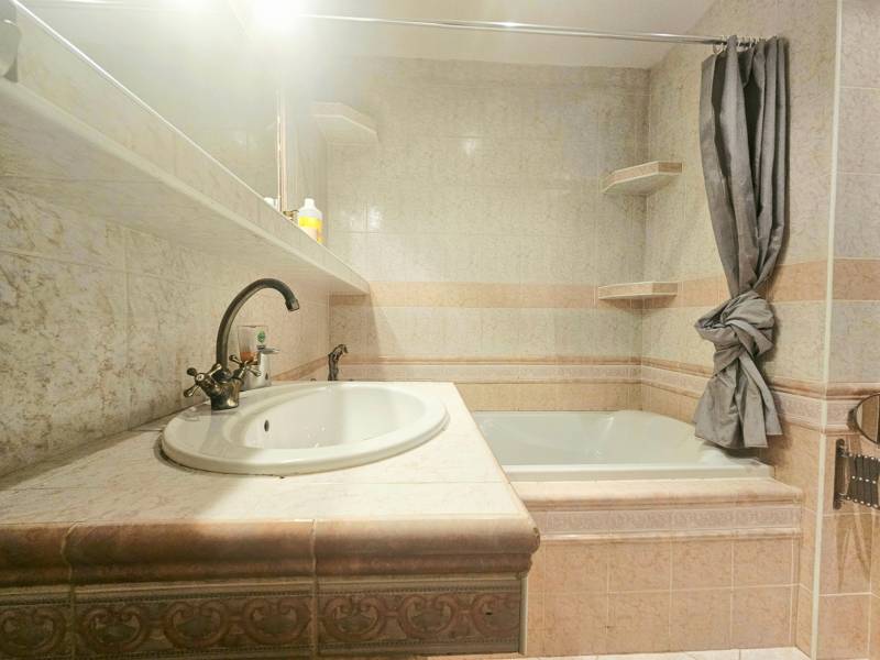 Bathroom in a 3-room apartment with a bathtub, sink, and tiles in neutral shades.