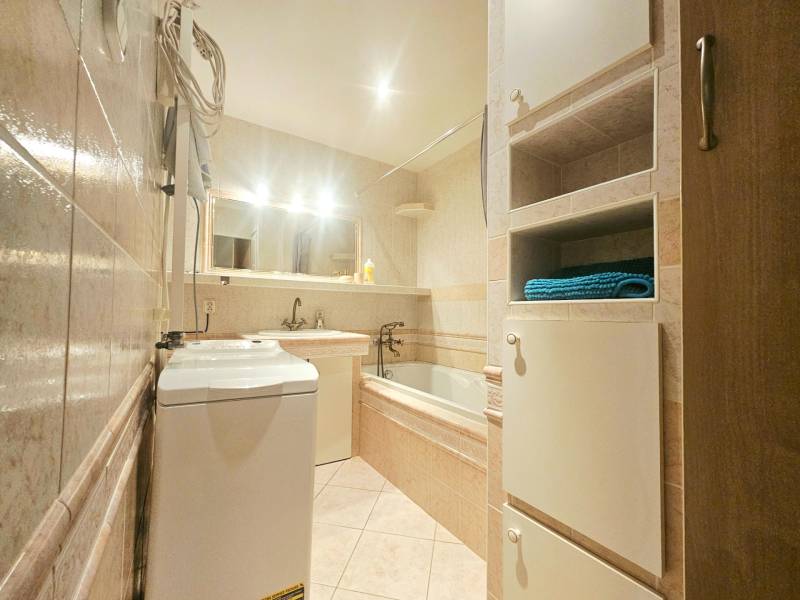 Bathroom with a bathtub, sink, washing machine, and storage cabinets in a 3-room apartment.