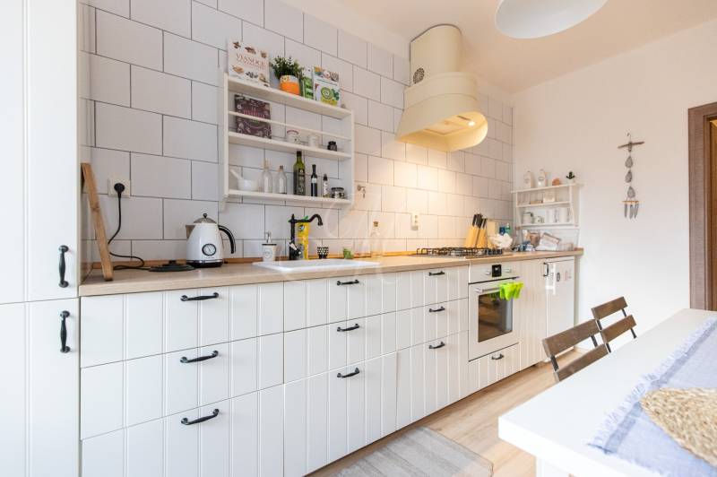 A kitchen in a 2-room apartment with a wooden decor floor and white cabinets.