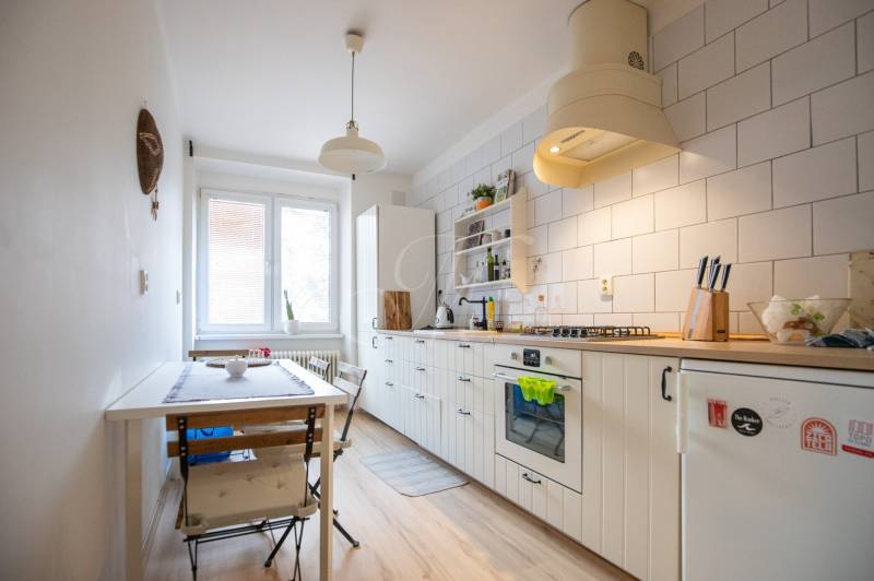 A kitchen with a wood-patterned floor and a dining table in a two-room apartment.