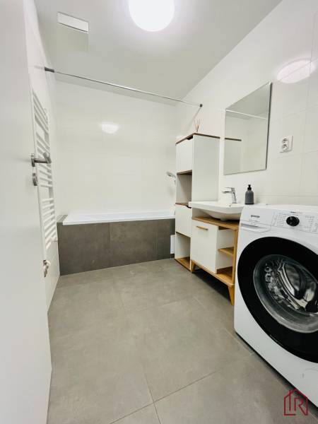 Bathroom with a bathtub, sink, mirror, and washing machine in a 3-room apartment.