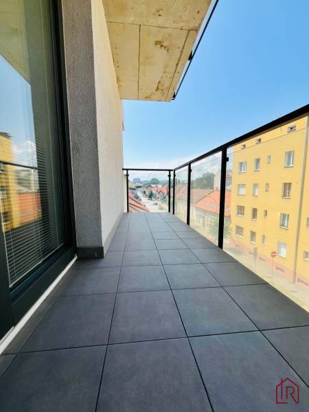 Balcony with tiles and glass railing, view of the street in a 3-room apartment.