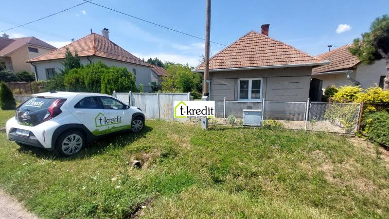 A family house in Nevidzany with a car in front of the house and greenery in the background.