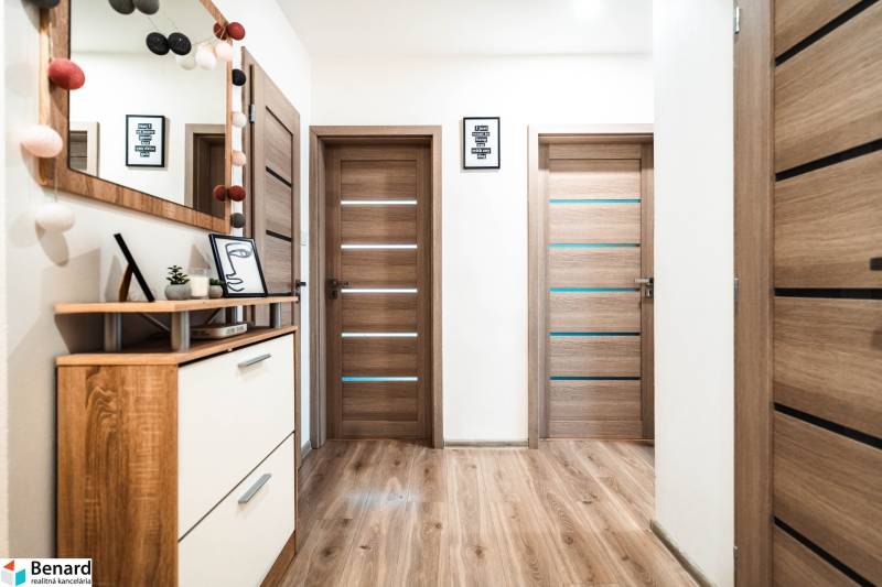 Interior of a 2-room apartment with a wooden decor floor, doors, and decorations.