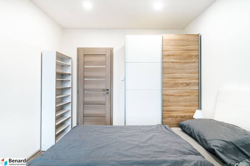 A bedroom in a 2-room apartment with a large wardrobe and a shelving unit.