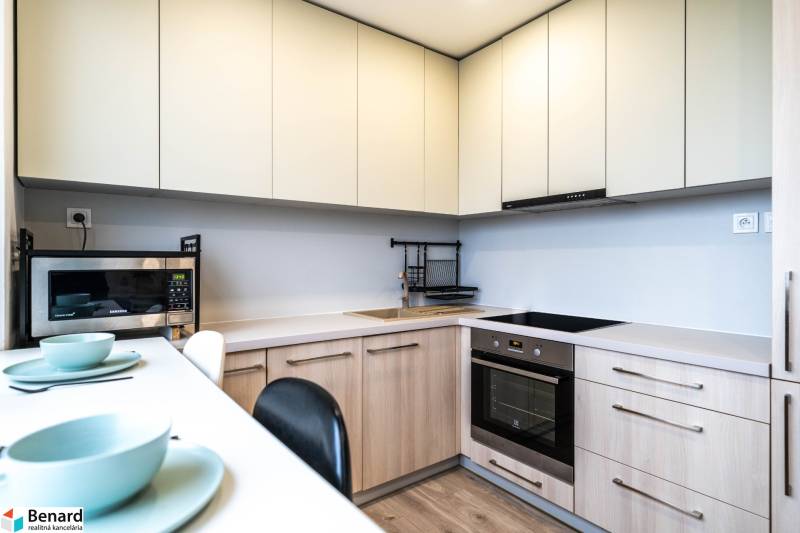 A kitchen in a 2-room apartment with white cabinets, a microwave, and a cooktop.
