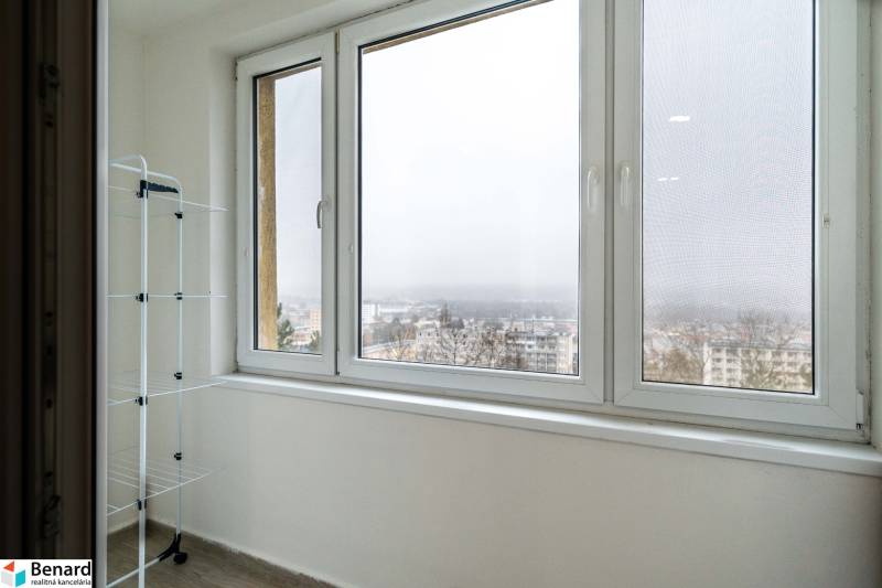 A balcony with a view in a 2-room apartment, a clothes rack, a city in fog.