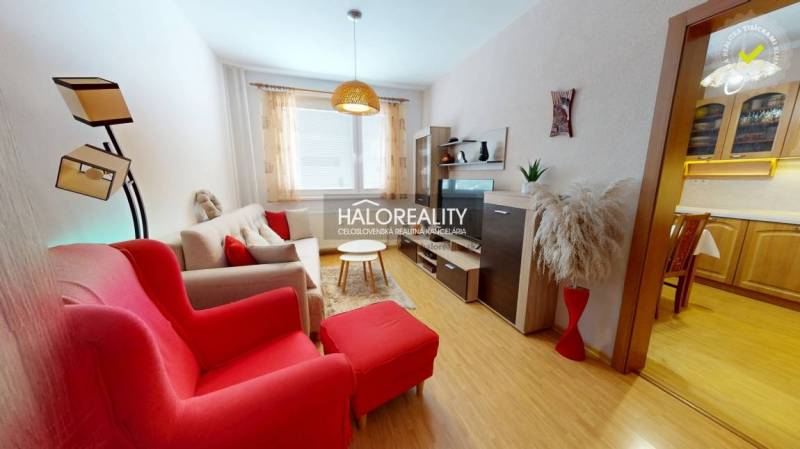 Living room in a two-room apartment with a wooden decor floor and red armchairs.