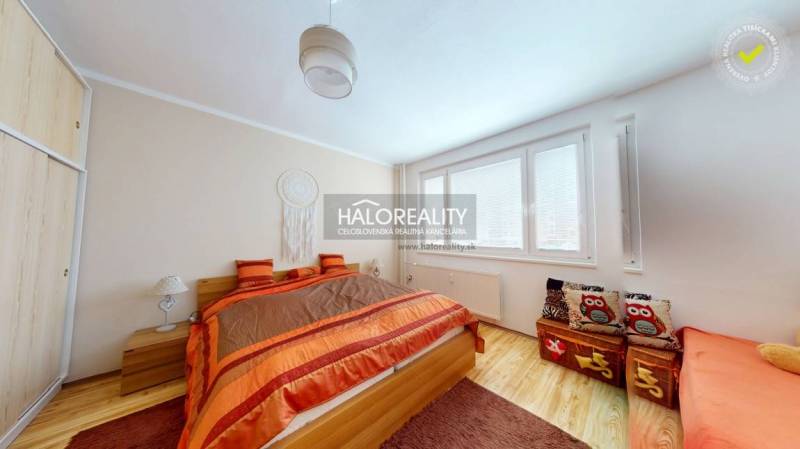 A bedroom with wood-patterned flooring in a 2-room apartment, cozy orange accessories.