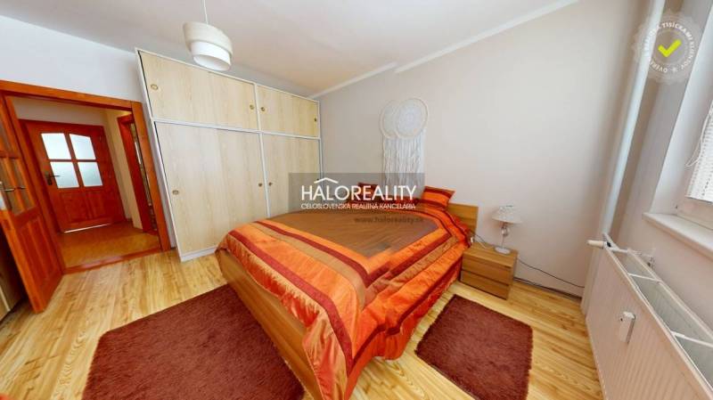 Bright bedroom in a 2-room apartment with wood-patterned flooring and a built-in wardrobe.