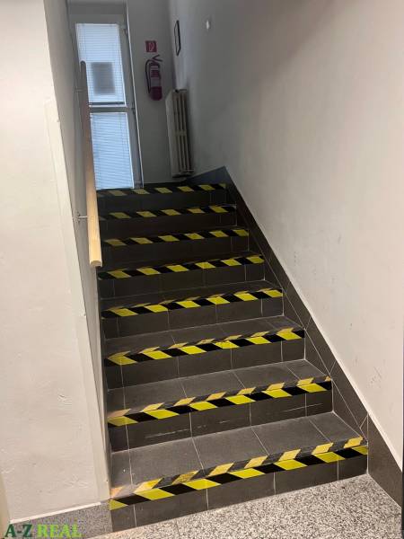 Staircase with support railing, marked with warning tapes in commercial premises.