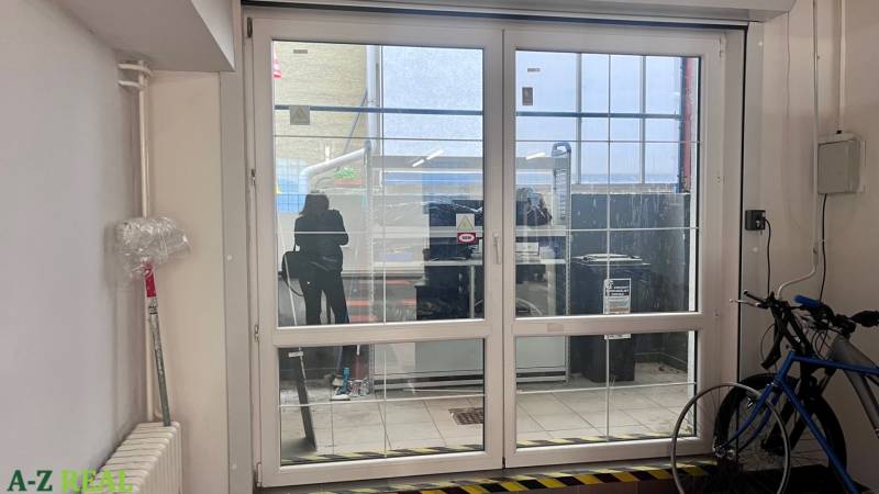 Glass sliding doors in commercial spaces, bicycle, radiator, and plastic film on the wall.