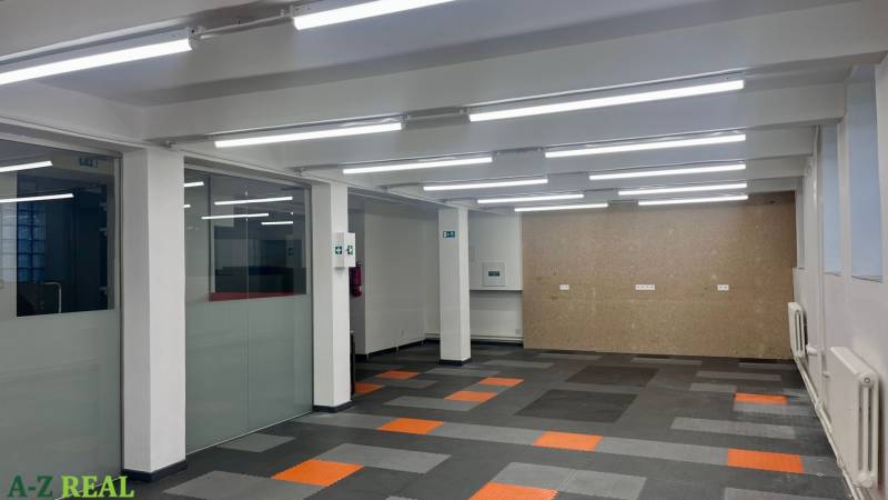 Commercial spaces with carpet flooring and glass partitions.