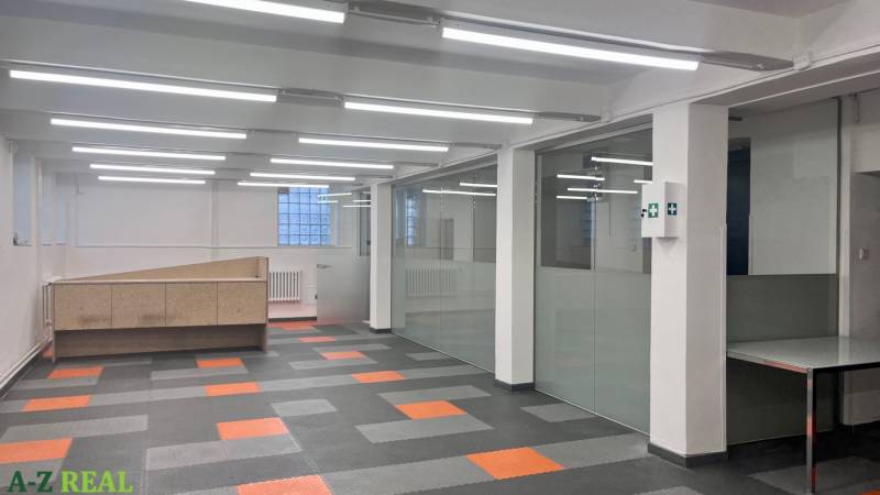 Commercial spaces with glass walls and patterned flooring with a wood design.