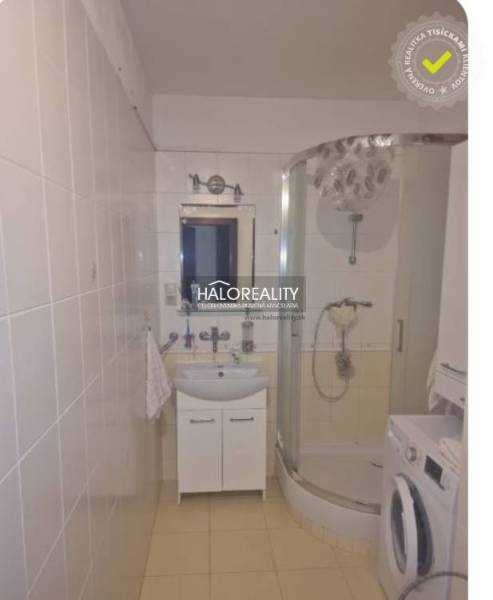 The bathroom of a three-room apartment with a corner shower and a washing machine.