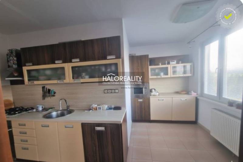 A kitchen in a 3-room apartment with dark cabinets and tiles, bright environment.